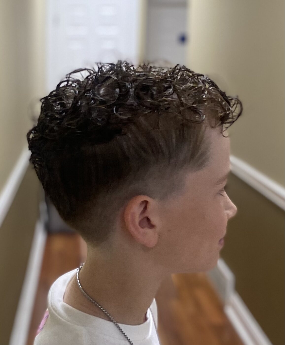 Boy's curly fade haircut viewed from the side