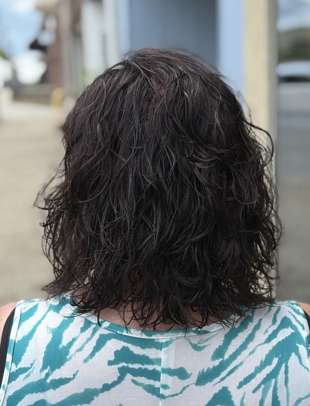 Dark shoulder-length hair with a fresh curl pattern